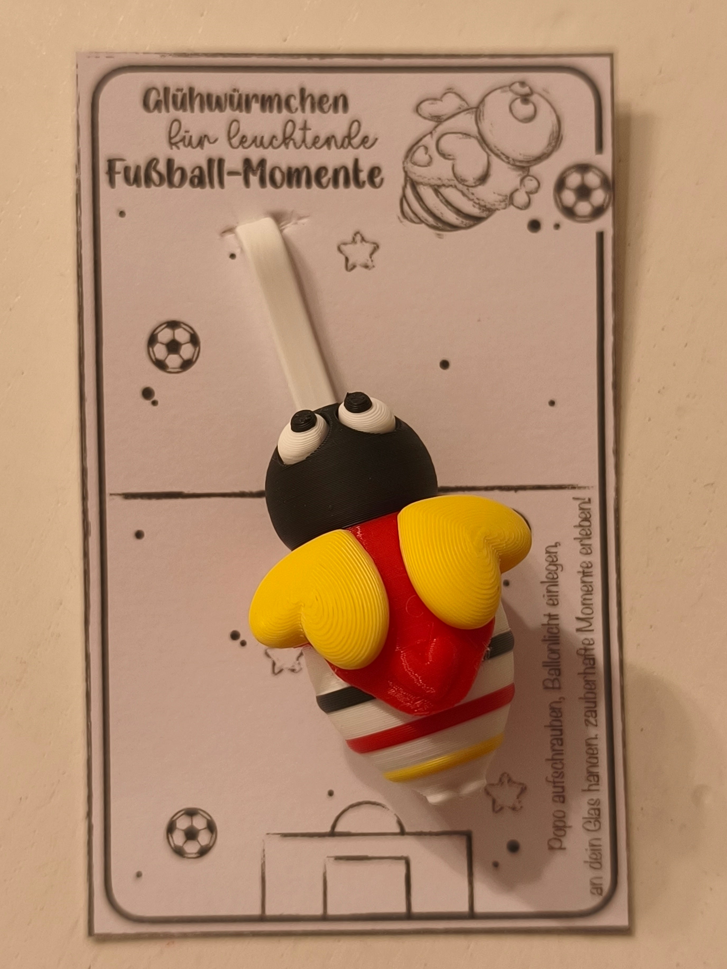 Fan-Irmchen Glasmarkierer – Leuchtendes Fußball-Glühwürmchen in Schwarz-Rot-Gold